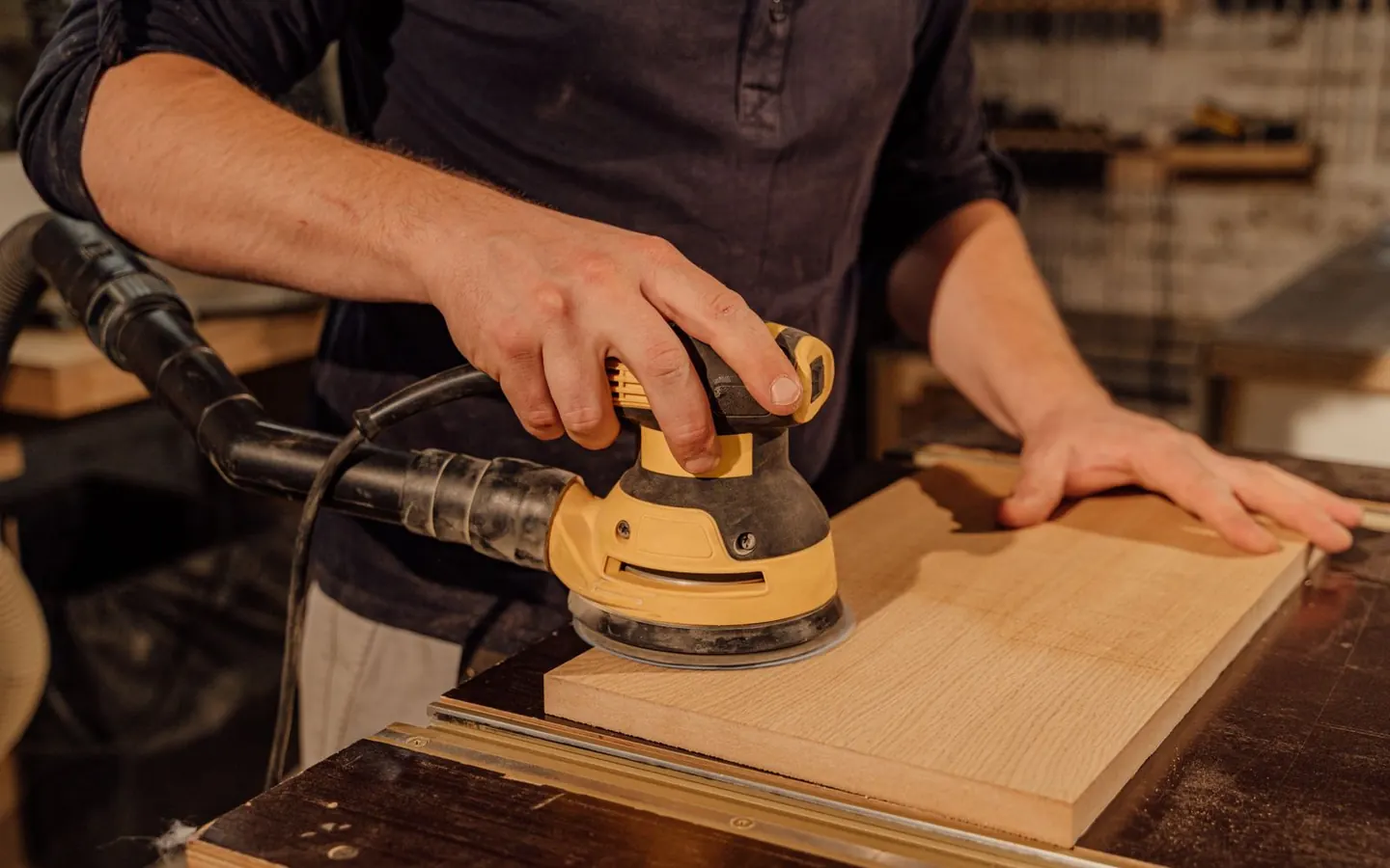 A carpenter sanding a wooden board in a workshop